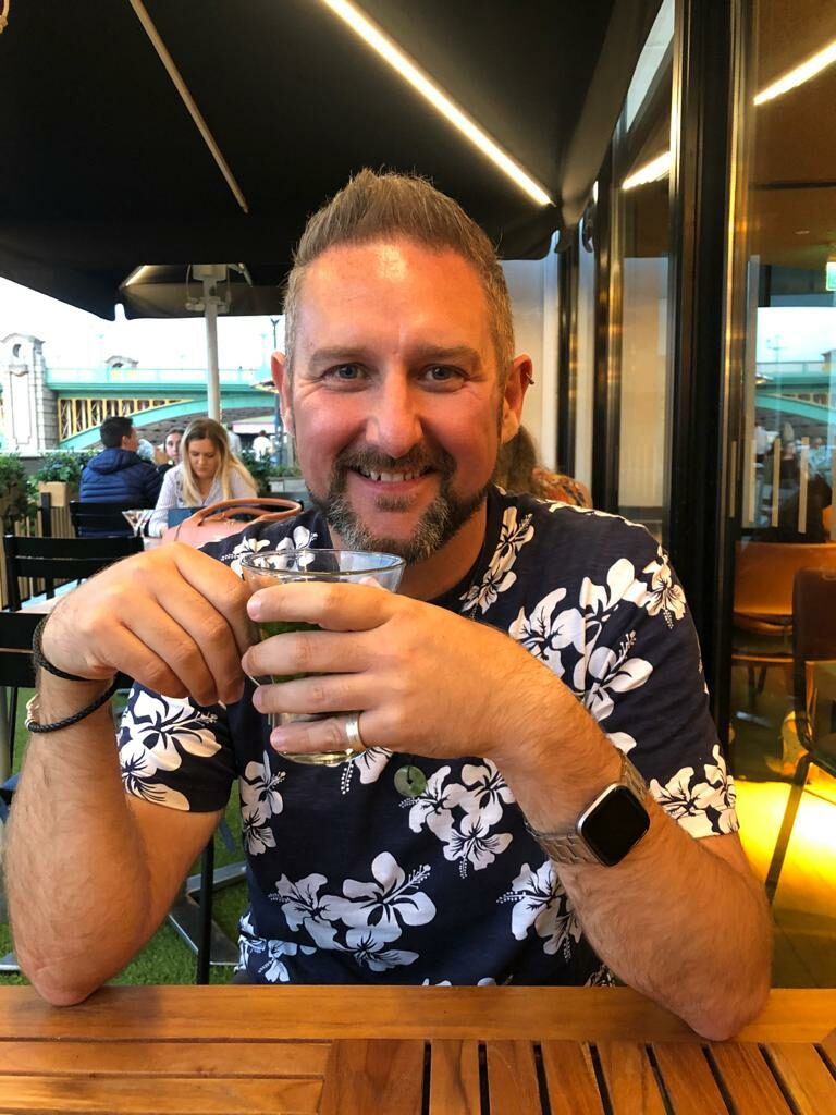 A smiling man in a floral shirt