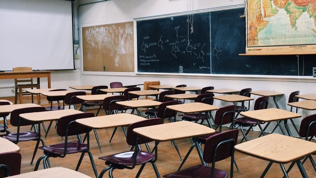 A school classroom with many desks and a blackboard