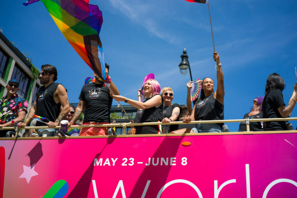 A group of people celebrating Pride on a pink bus