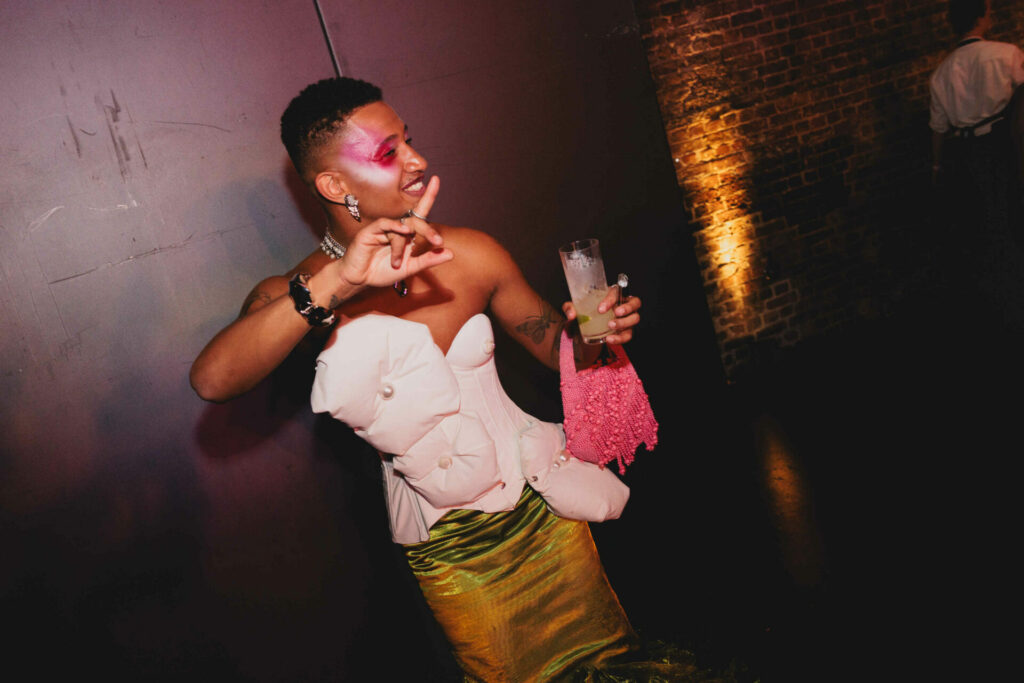 Tyreece holding a glass in a white and green dress