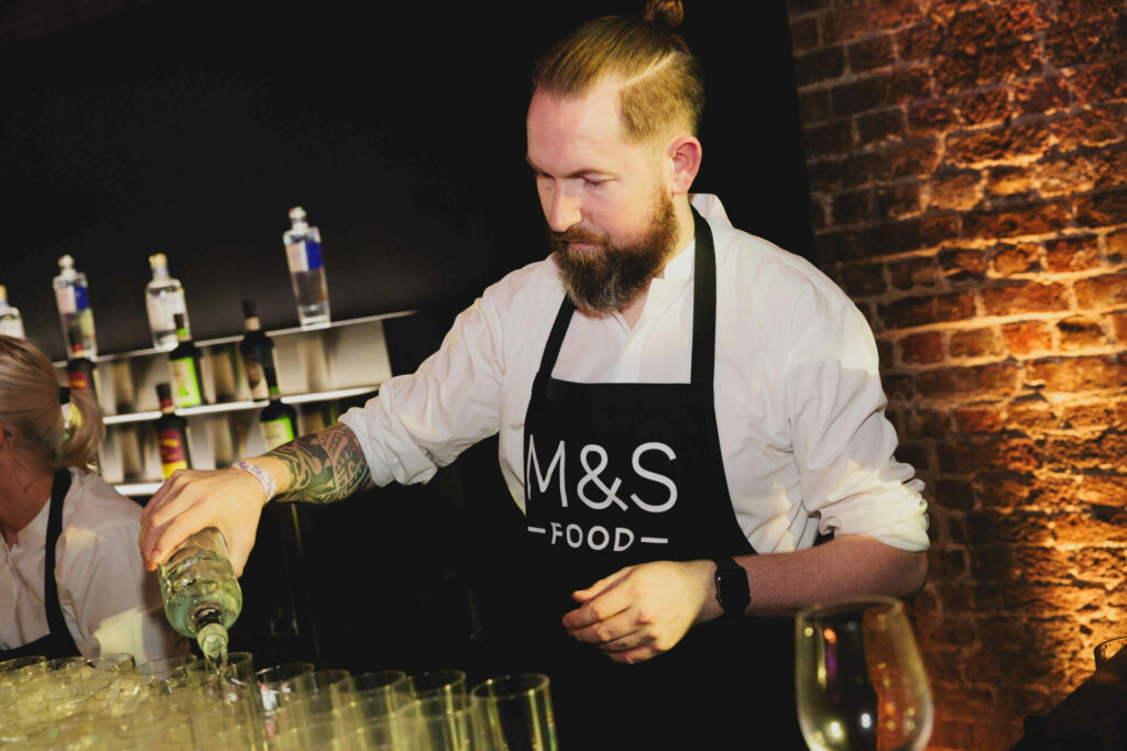 A man in an apron pouring drinks