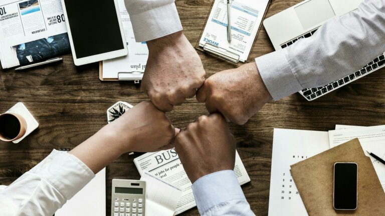 Four fists bumping over a table of business materials