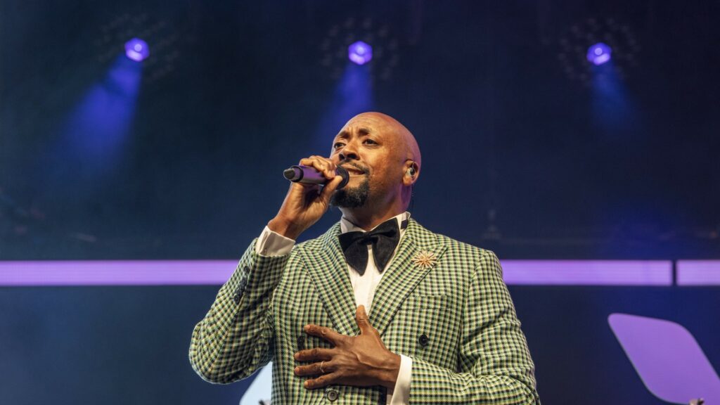 Matt Henry on stage wearing a green suit holding a microphone