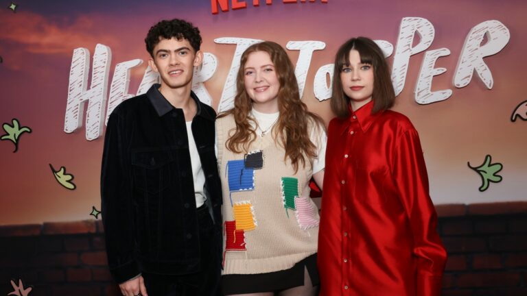 Joe Locke, Alice Oseman, and Jenny Walser on the red carpet standing against a backdrop that says Heartstopper