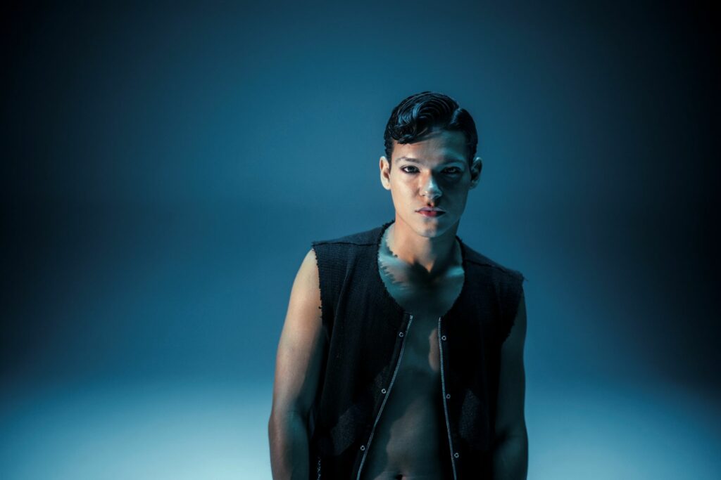 Omar Rudberg in a black waistcoat against a blue backdrop