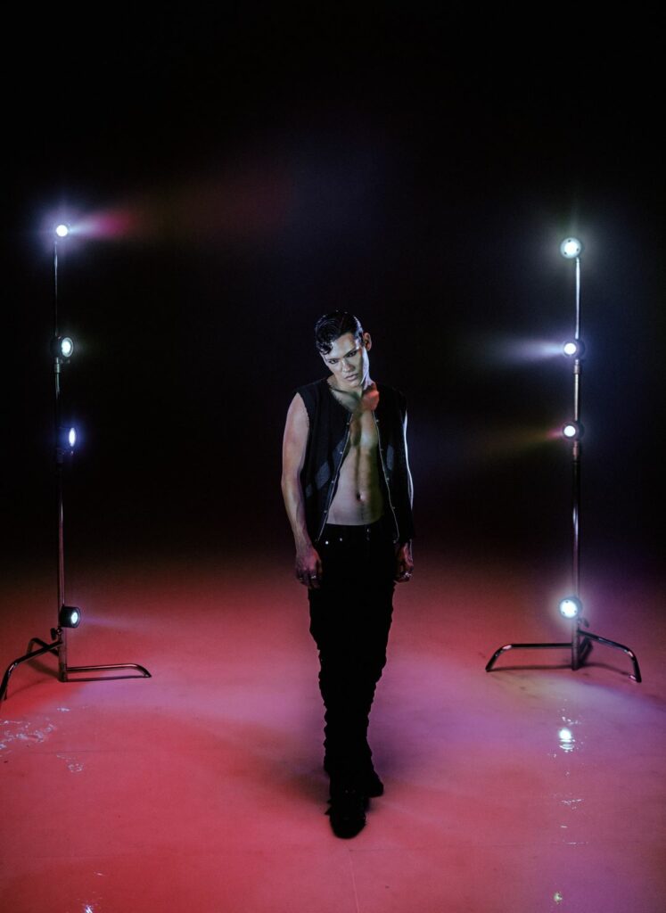 Omar Rudberg in a black waistcoat against a red backdrop