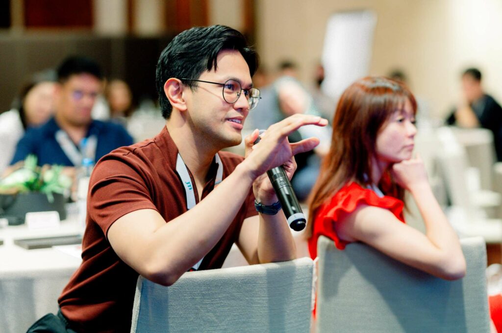 A man holding a mic sitting on a chair