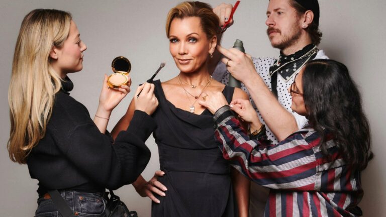 Vanessa Williams smiling into the camera while people apply her makeup