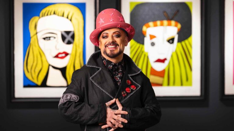 Boy George standing in front of his Madonna portrait and a self-portrait