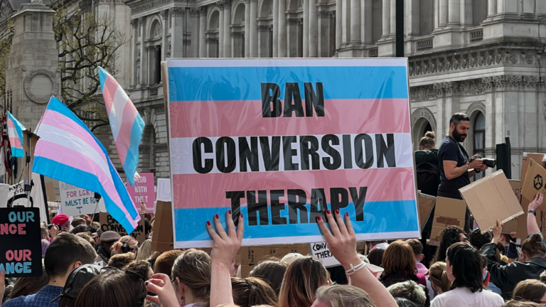 A posted with the tran flag that says "Ban Conversion Therapy" LGBTQ+