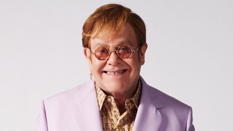 Elton John in a recent photoshoot for Attitude, in a purple suit (Image: Attitude)