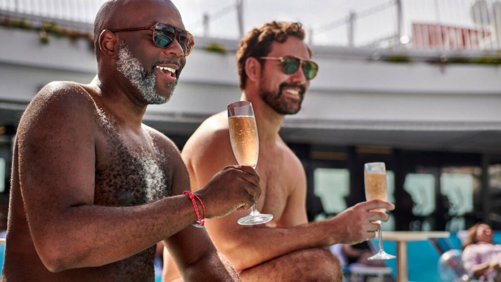 Two men hold champagne flutes in a hot tub