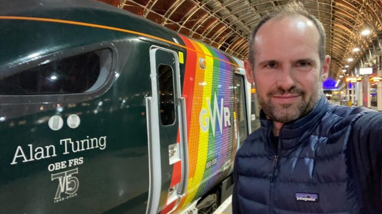 A smiling man standing in front of a train inside a museum