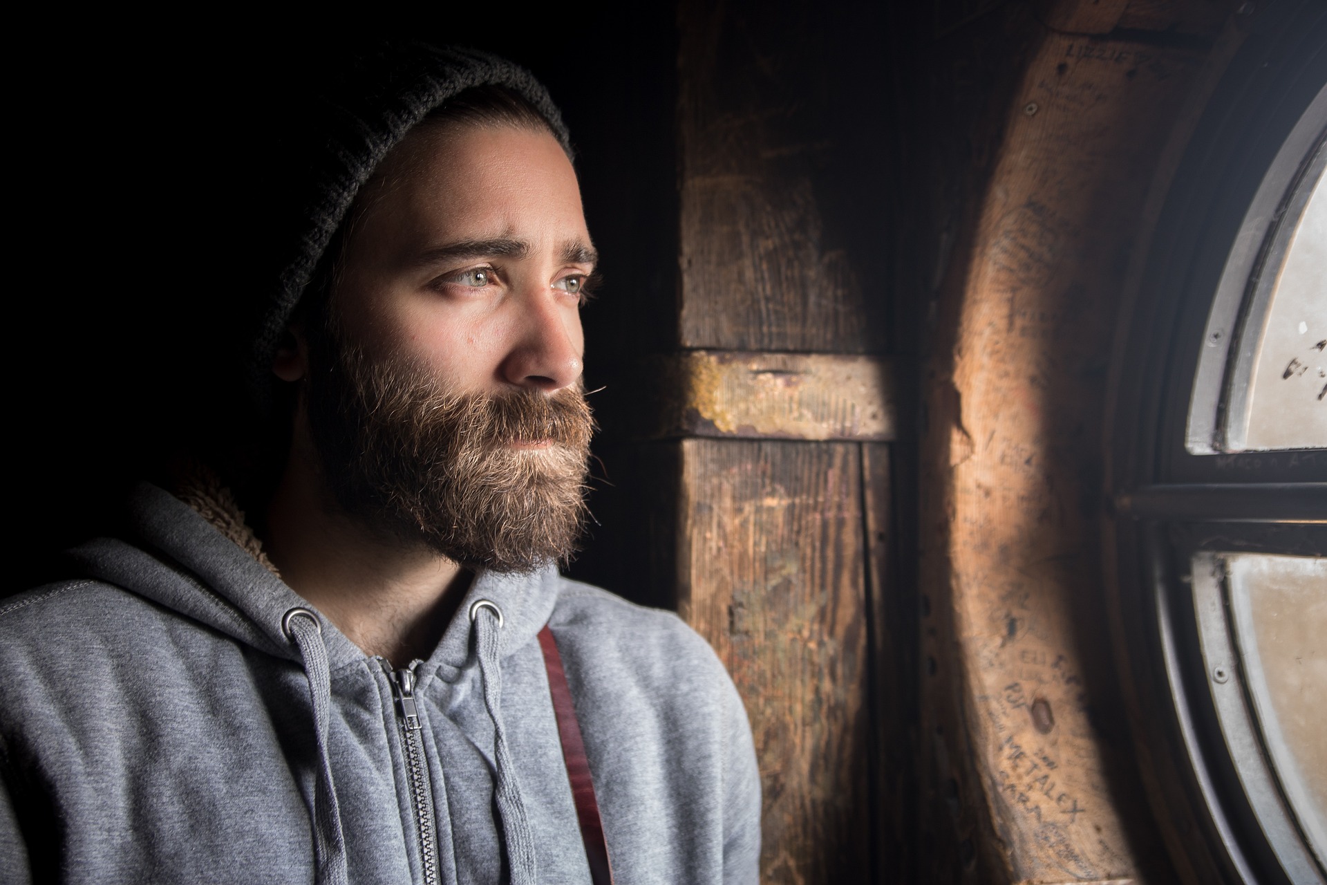 a man in a beanie looking out a window