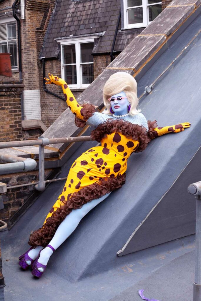 Juno Birch in a yellow dress posing on a rooftop