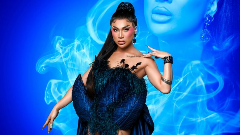 Zahira from Drag Race UK against a blue backdrop