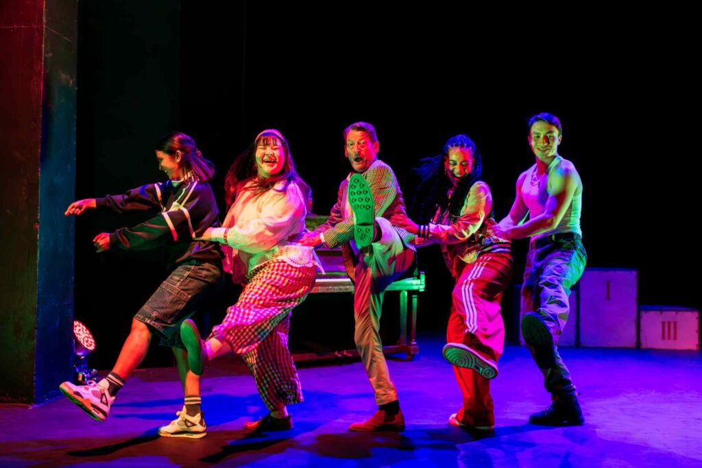 Actors onstage dancing a conga line