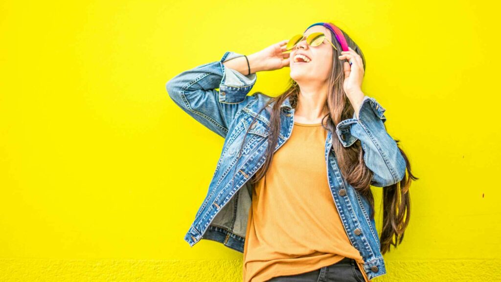 A smiling woman against a yellow backdrop