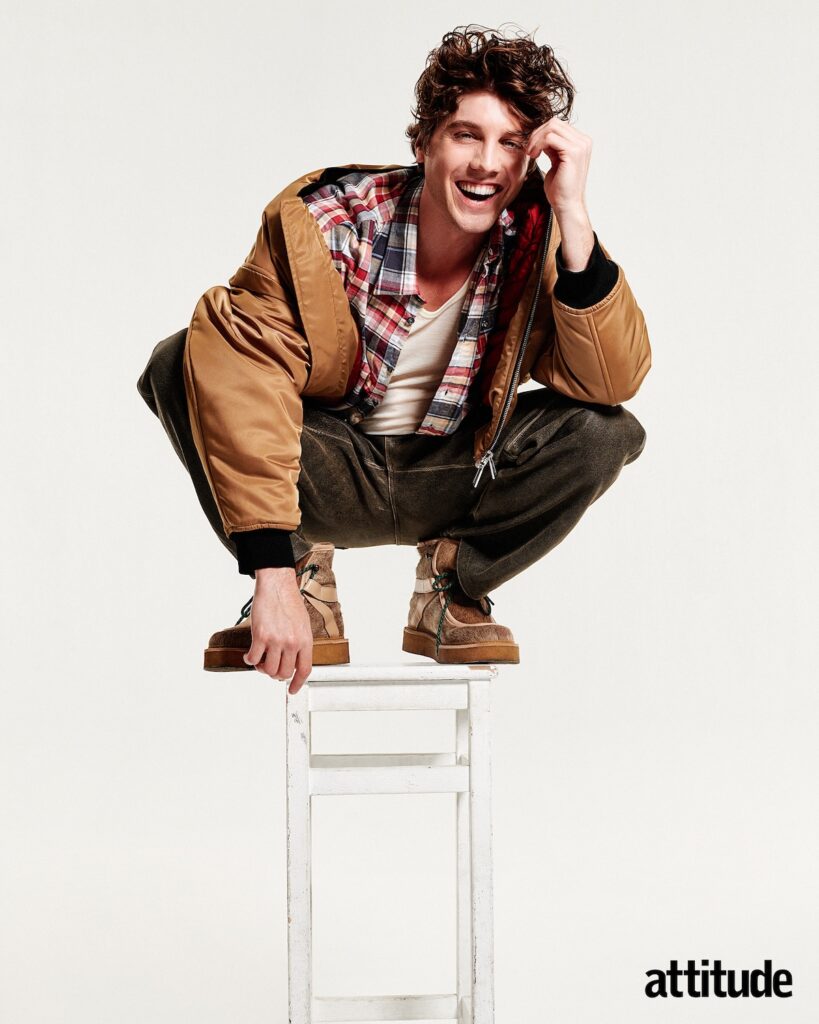 Lukas standing and crouching on a stool in a tan jacket