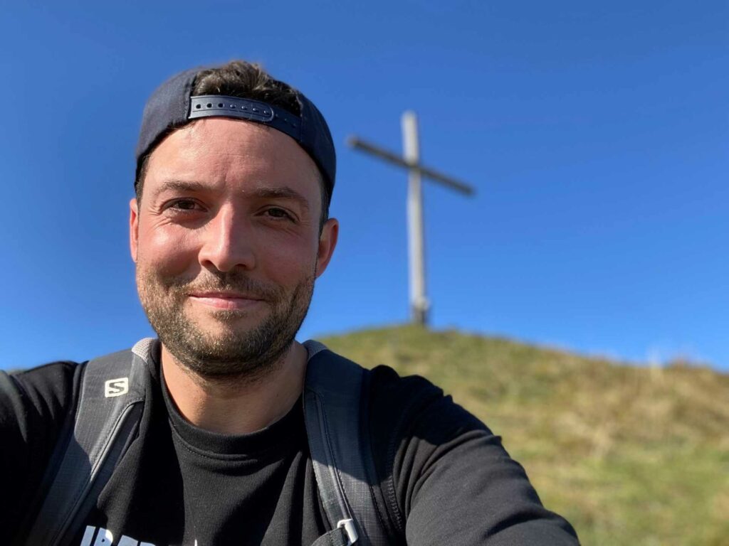 A smiling man standing by a hill