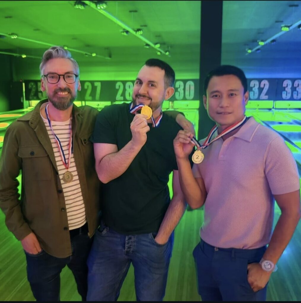 Three smiling people holding medals