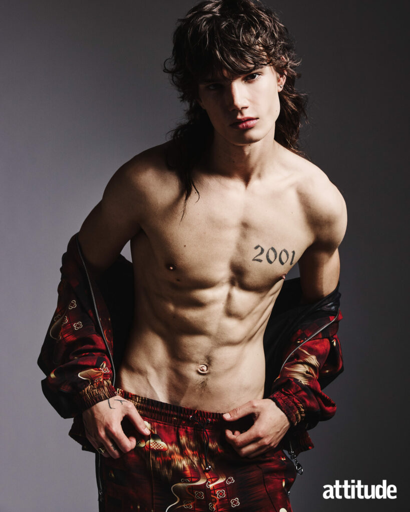 Model poses topless with a printed red jacket and trousers