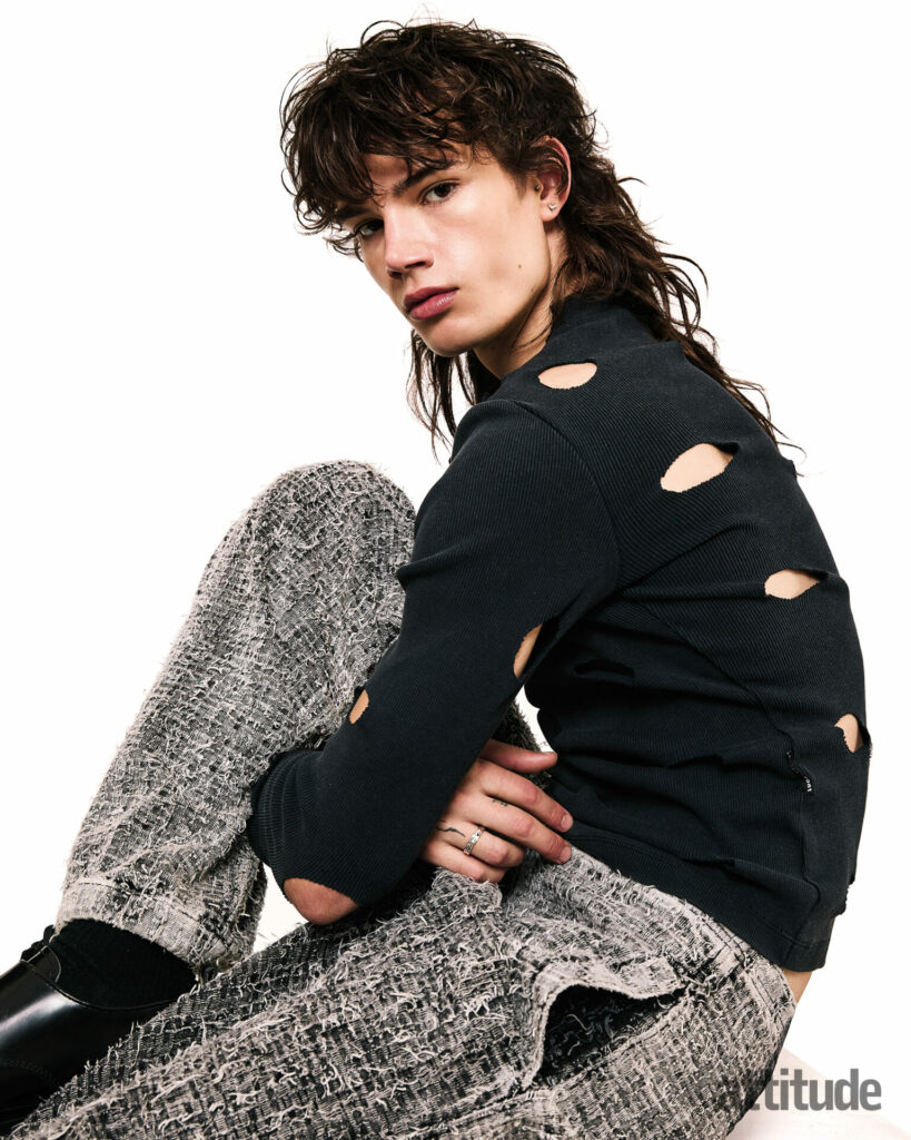 Model poses with cut-out black long sleeve and grey trousers