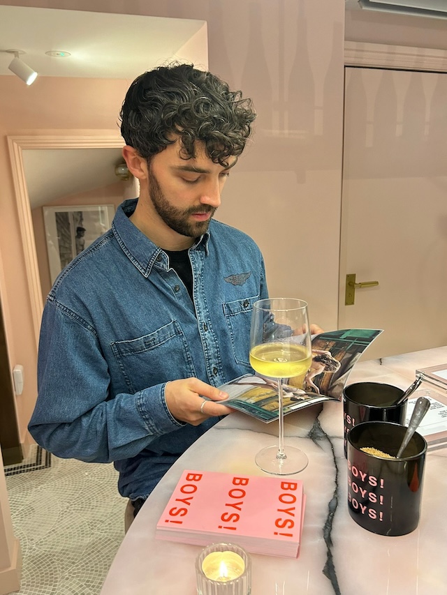 a visitor looking through a magazine and having a class of wine