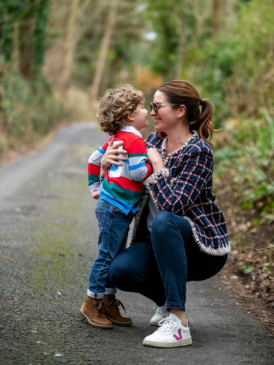 A woman and child crouch down smiling at each other