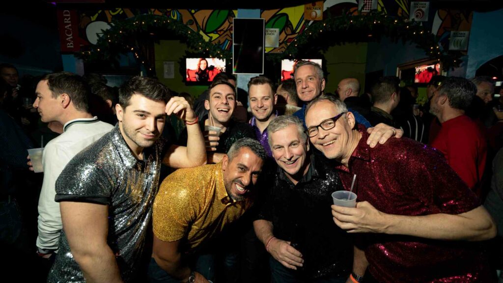 A group of smiling man inside a nightlife venue looking into the camera