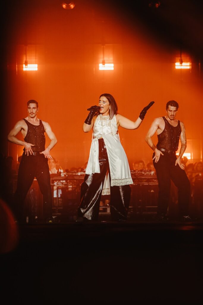 Jessie Ware on stage in a white dress