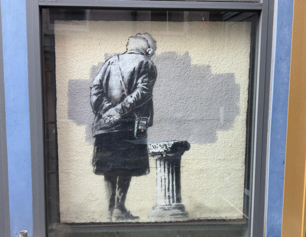 A view of the artwork Art Buff by Banksy inside plexiglass