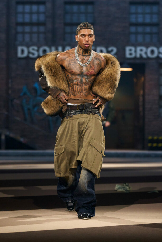 NLE Choppa walks the runway topless with fur scarf and low waist, oversized cargo and denim trousers