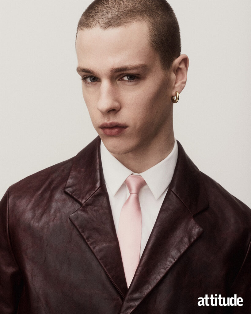 Close up shot of model in burgundy leather jacket, white collar shirt and pink tie