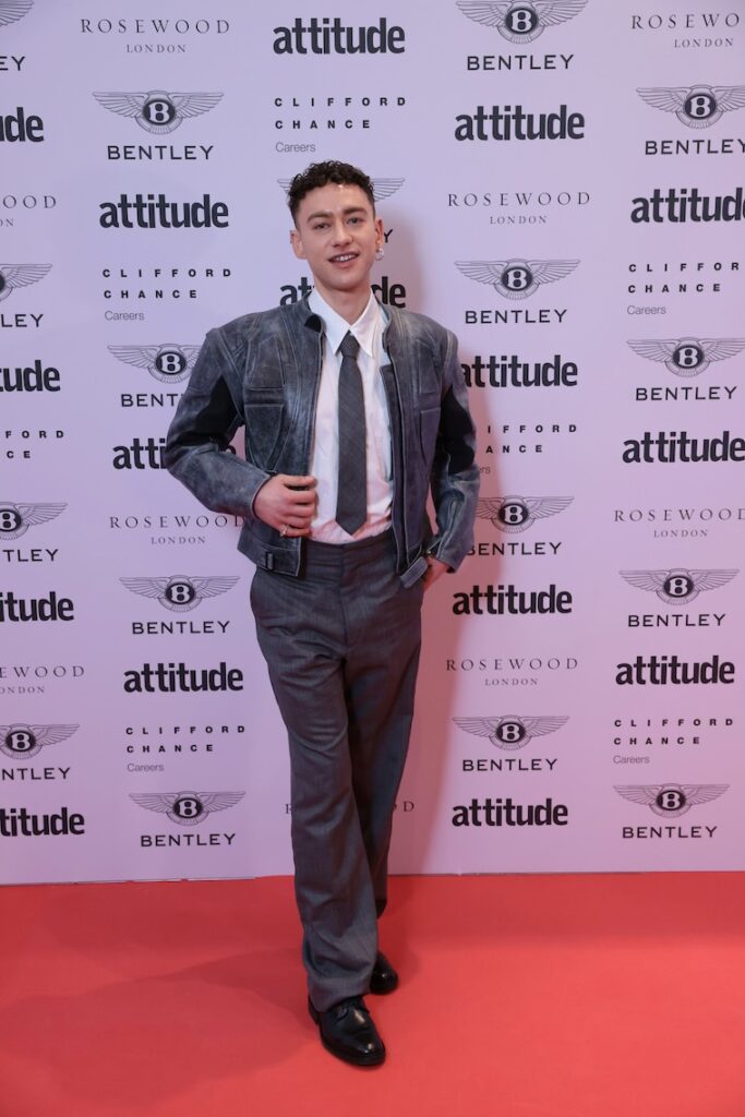 Olly Alexander in a suit, tie and leather jacket