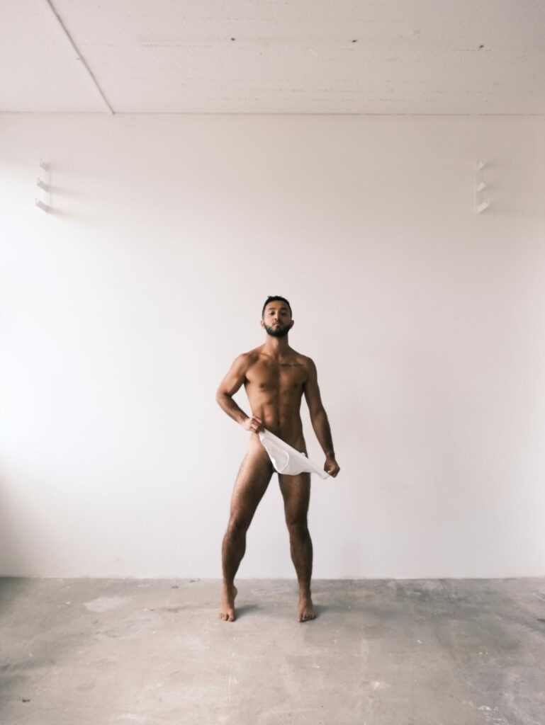 a man in a white room pulling down his white underwear