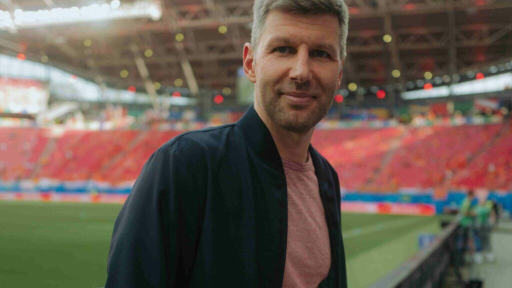 Thomas Hitzlsperger standing in a football stadium looking into the camera smiling