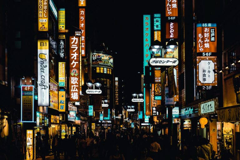 View of a Tokyo neighbourhood at night with neon signs and people walking in the streets