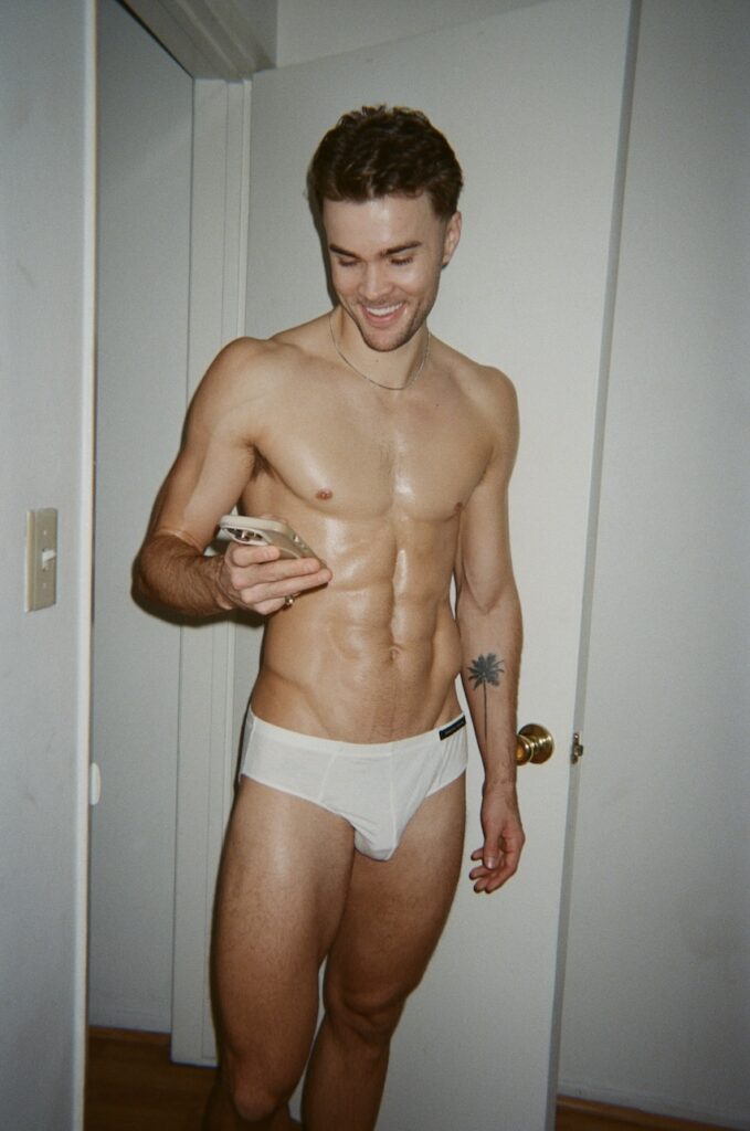 a man in white underwear checking his mobile phone