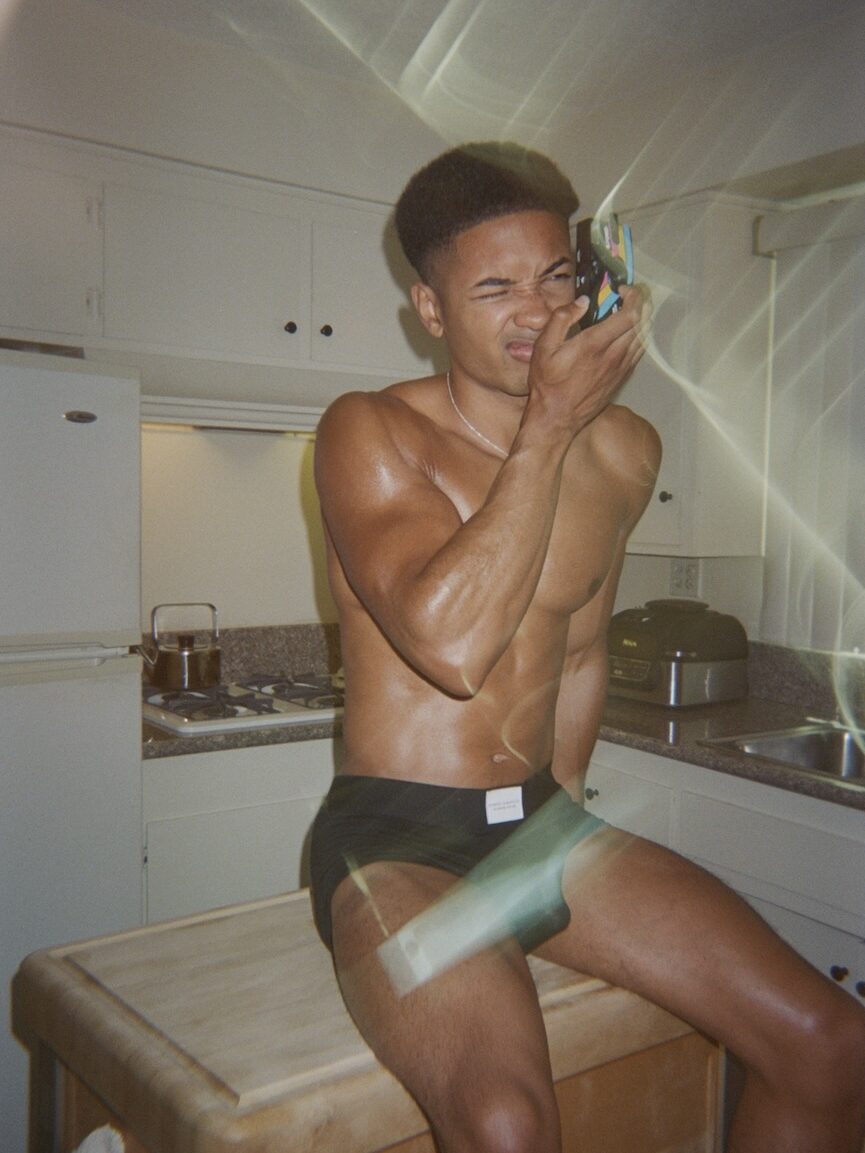 a man sat on a kitchen counter in black briefs