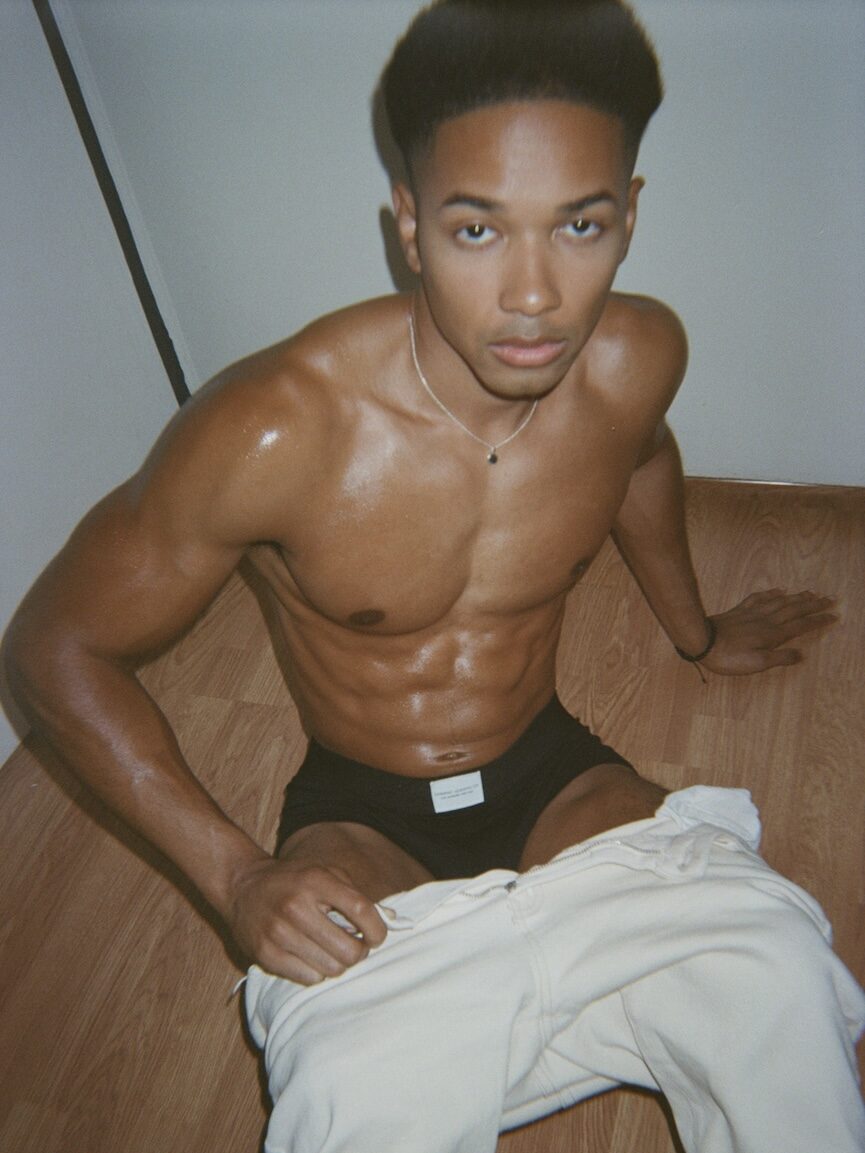 a man topless in black briefs with tracksuit bottoms pulled down