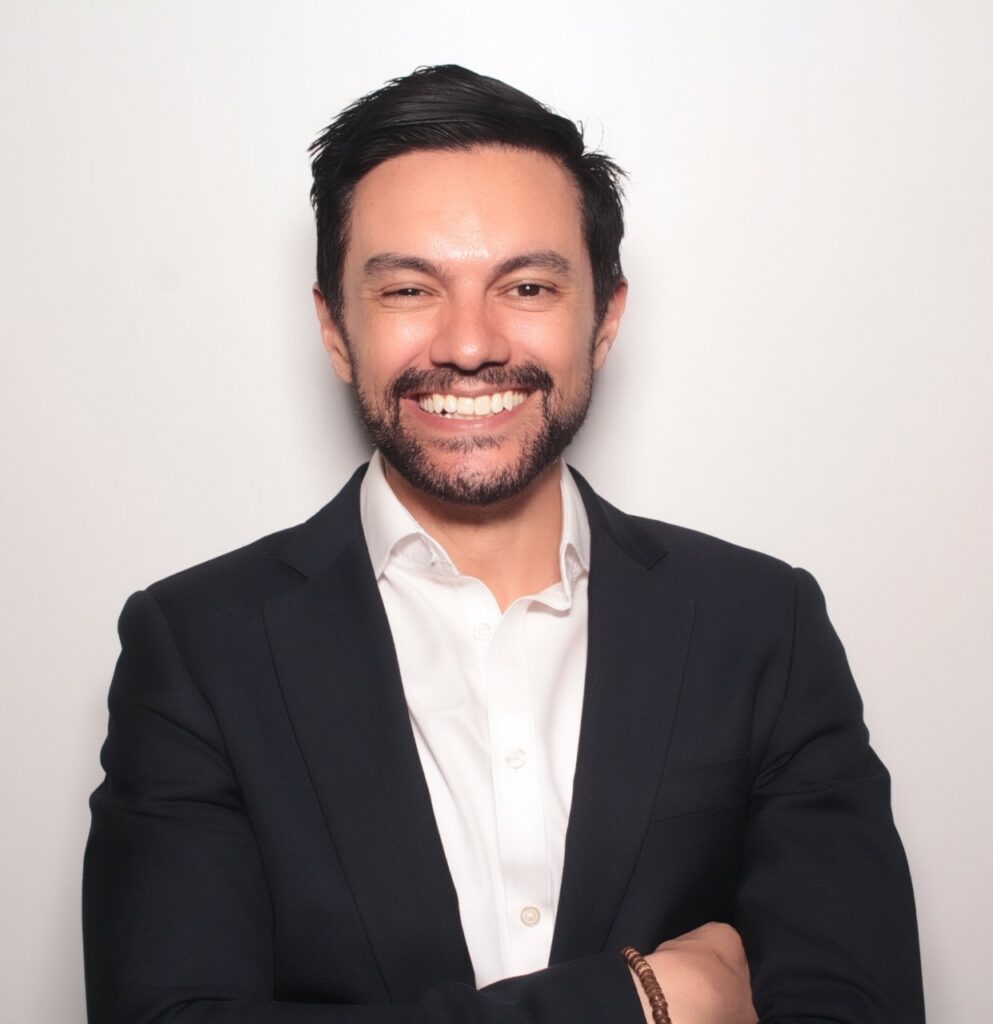 A smiling man wearing a white shirt and black jacket