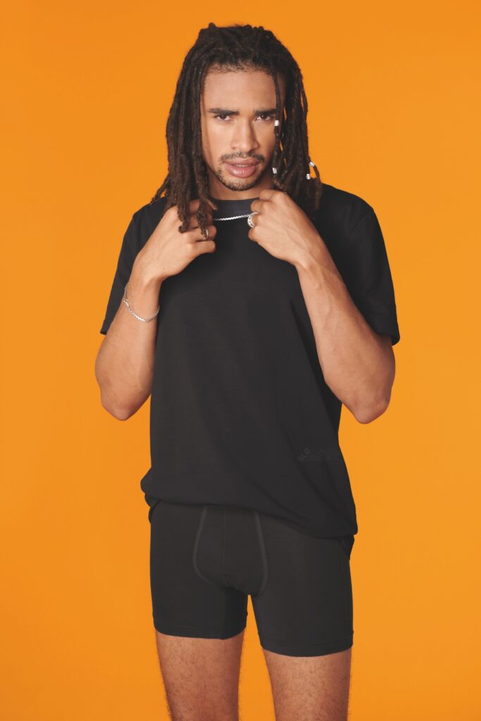 a man with dreads in a black t-shirt and shorts