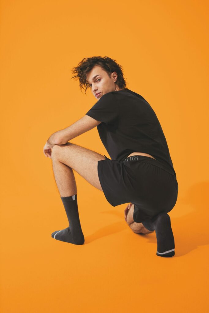 a man in black garments kneeling and looking over shoulder