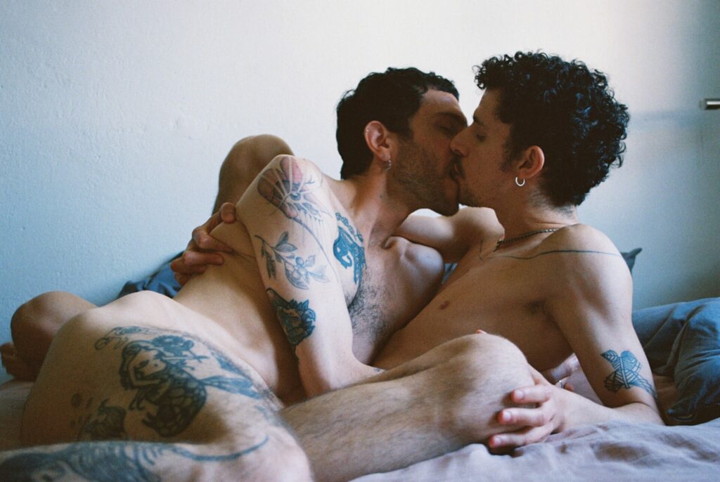 two men in bed kissing