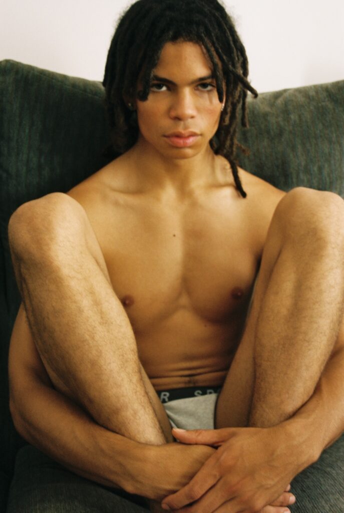 a topless person in underwear sitting on a sofa