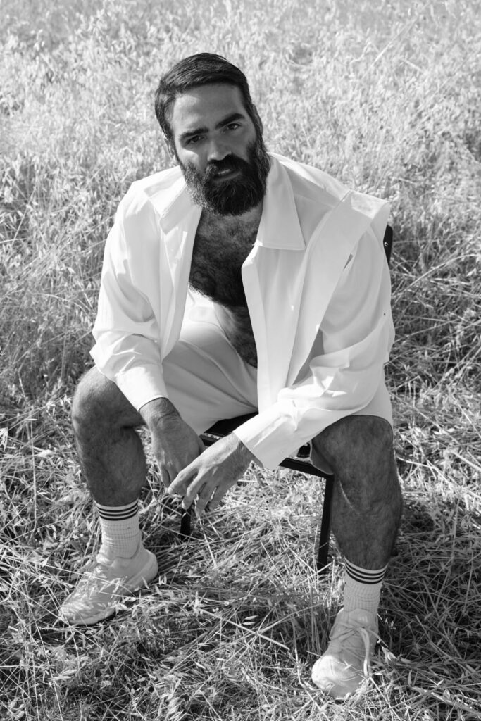 Black and white portrait of Yorgos Tsiantoulas sitting on a chair in a field of straw