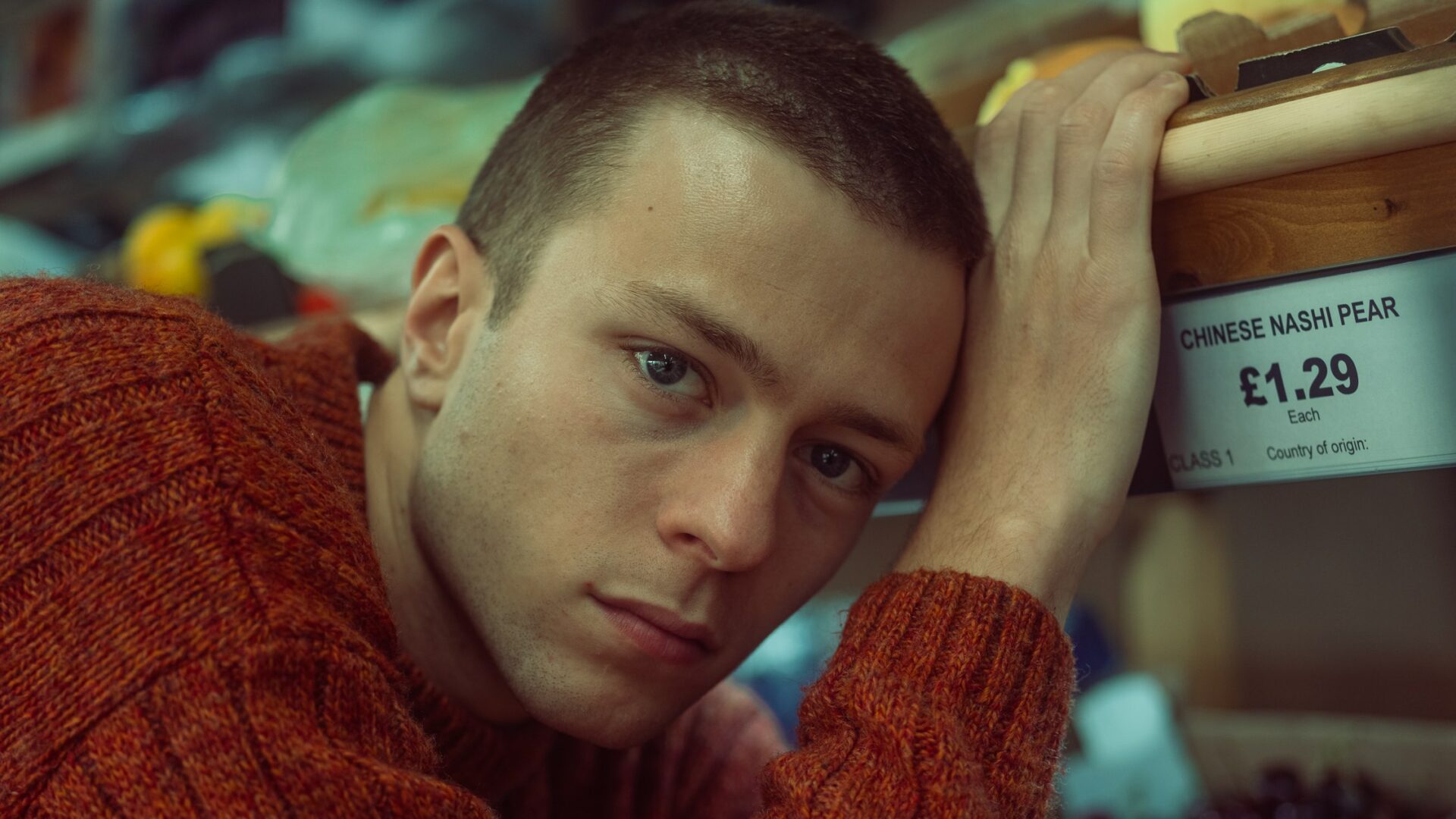 A picture of the interview in an orange sweater standing in a grocery store